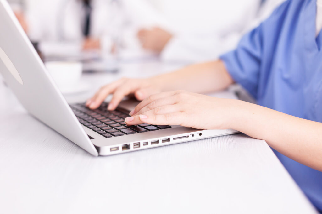 Close up of medical nurse typing on laptop